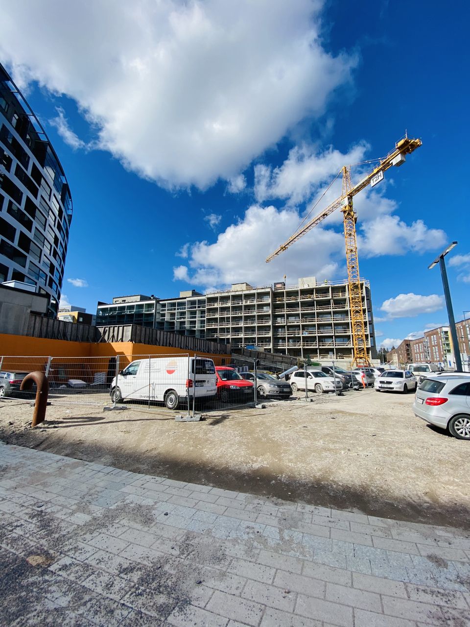 Kerrostaloja ja rakennustyömaa nostureineen sinisen taivaan alla.